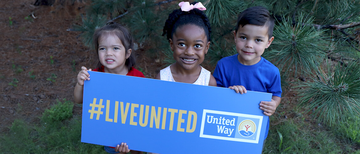 Three children hold a sign that says, "#LiveUnited."