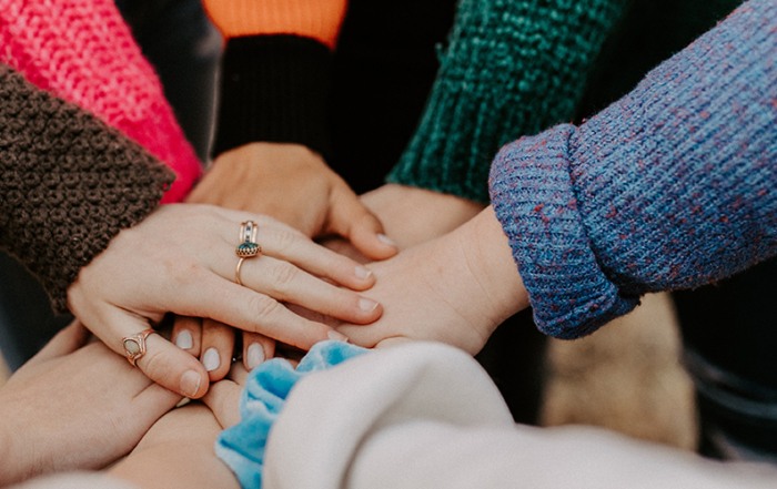 A team of young people stack hands in a circle.