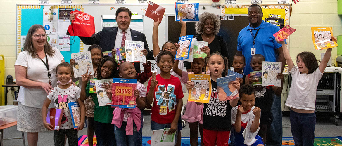 A class of third grade students pose with the books they received as part of United Way's Coaching for Literacy program.