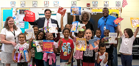 A classroom of students pose with new books they received from United Way through the Coaching for Literacy initiative.