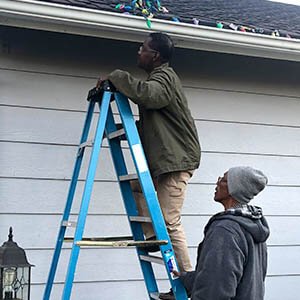Aubrey Mentis, United Way Community Impact Manager for Health, hangs Christmas lights on his house with his dad.