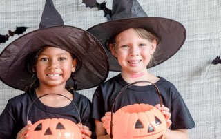 Two elementary age girls are dressed up as witches for Halloween.