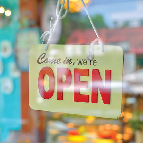 A open sign hangs in the window of a small business.