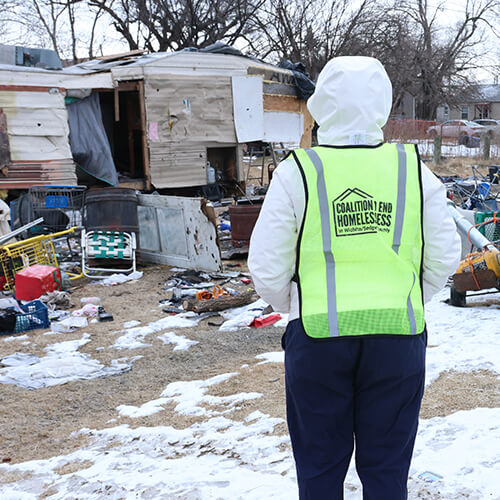 A Coalition to End Homelessness volunteer approaches an encampment to see what services they can provide to the people living there.