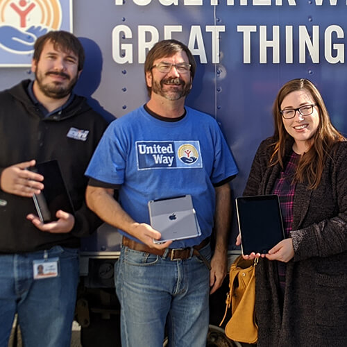 Corporate supporters pose beside the Give Items of Value box truck with the computer equipment they're donating.