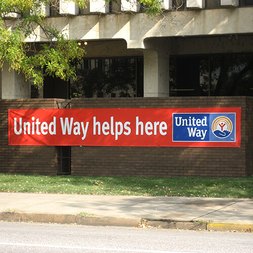 Red "United Way Helps Here" hanging on a fence outside a funded partner's office.