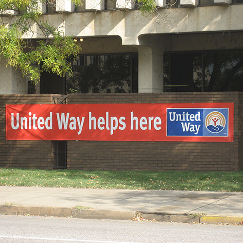 Red "United Way Helps Here" banner hanging on the fence.